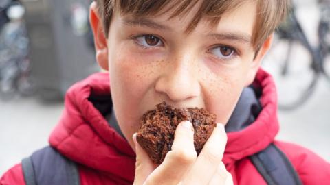 A young boy eating a chocolate muffin.