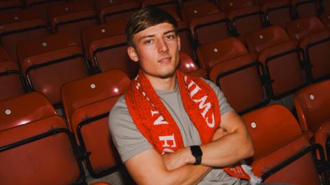 Joe Snowdown sat with a Swindon scarf on