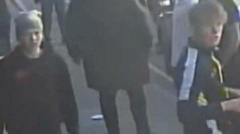 Two young males captured on blurry CCTV image walking down a street.