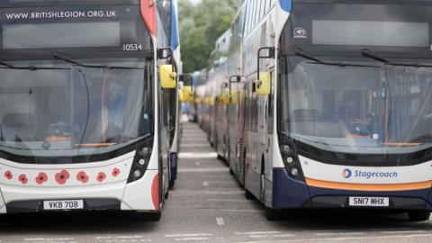 Two Stagecoach branded double decker buses parked side by side, one also decorated with pictures of Remembrance Day poppies.