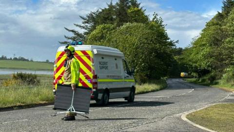 Incident support vehicle and man in uniform standing on a country road