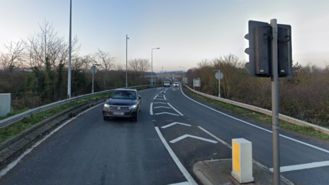 Junction 11 of the M25. A few cars on the road, blue sky above.