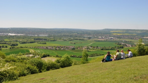 Four people sat at the top of the hill overlooking lots of green fields
