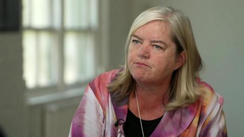 Louise Casey, Baroness Casey of Blackstock, speaking with BBC News. She is looking slightly to her right and is wearing a pink and white marbled jacket.