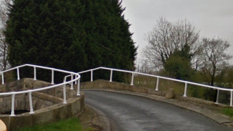 The road bridge curving to the right with white railings on either side