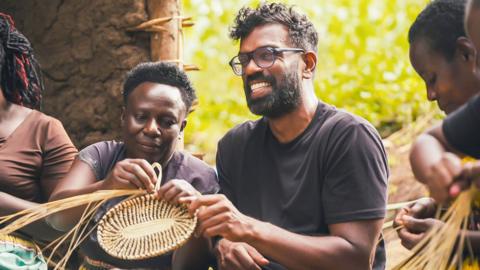 a group of people building an object using tree branches