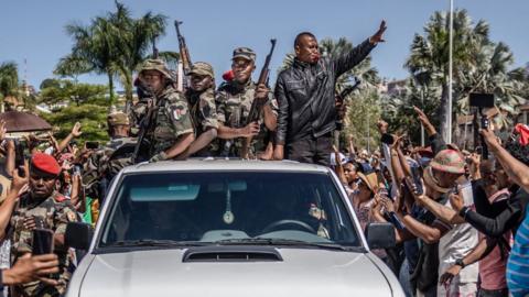 Members of a section of the Malagasy army on a pickup truck are greeted by residents gathered for a ceremony honouring protesters killed in anti-government protests in Antananarivo on October 12, 2025
