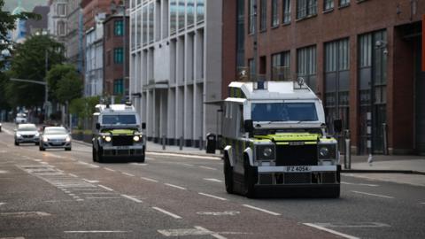 armoured police landrovers driving on quiet Belfast street