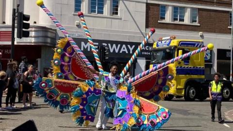A man in a colourful costume in a carnival parade
