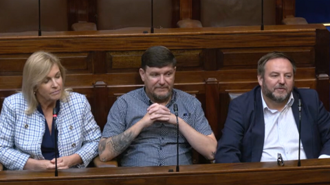 A woman and two men sitting in the Dáil