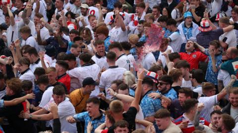 A crowd of men in football shirts jump and wave their arms in celebration at the theFans Central Park Fan Park in Newcastle watching the UEFA Euro 2024 Group C match between Denmark and England.
