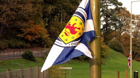 A Saltire wit a crest and a Union flag on lampposts on a road near Cameron Barracks in Inverness.