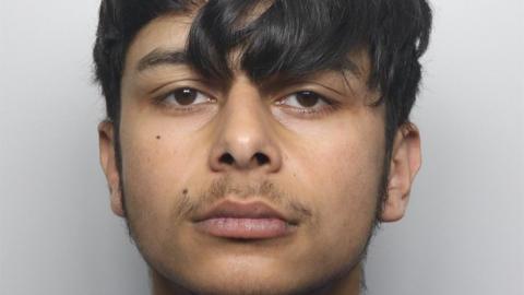 A mugshot of Kubalik who has brown hair styled over his forehead and brown eyes. Two moles can be seen on the right side of his face and he has facial hair on his upper lip.