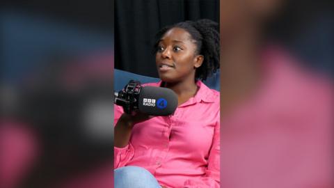 Psychologist Kimberley Wilson sits behind a BBC Radio 4 mic. She has black hair and wears a bright pink shirt