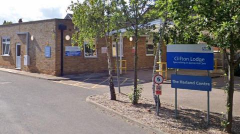 A google maps image of a care home building. There is a sign outside that reads "Clifton Lodge, specialising in Dementia care".
