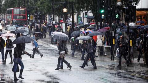 Shoppers and commuters with umbrellas on a rainy day in central London.