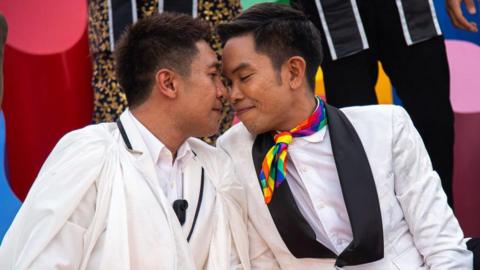 A gay couple - two men - sit close together with their heads touching as they pose for a photo during a celebration hosted by the Thai government to mark the passage of the marriage equality bill in June

