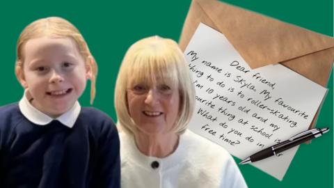 A young girl with an older lady next to them is a hand written letter, an envelope and pen. 