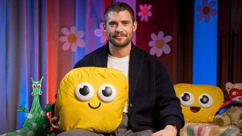 David Corenswet holding the Cbeebies yellow mascot.