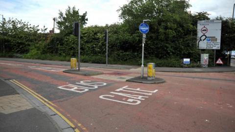 A view of a road with the sign 'Bus Gate' on one of the lanes