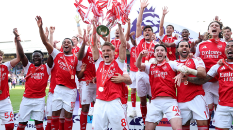 The Arsenal squad celebrate with the Premier League trophy