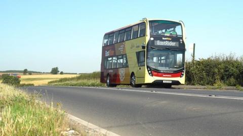 An East Yorkshire Buses double-decker bus on a road in the countryside under clear blue sky.