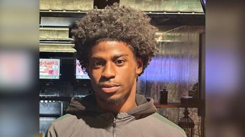 Rinneau Perrineau is looking at the camera wearing a neutral expression