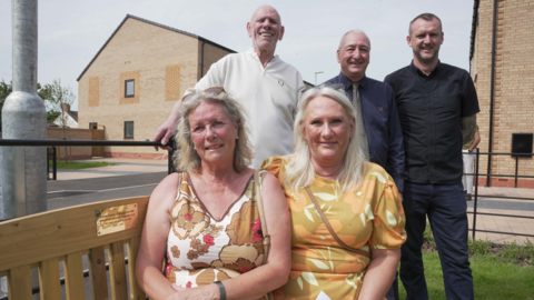 Noreen’s daughters, Dawn Radford and Lynne Daffern, sit on the bench by the plaque. They have patterned summer dresses on. Son, Alan Turner is stood behind with deputy leader Steve Evans, and Morro Partnerships Contracts Manager, Matt Jenkins. 