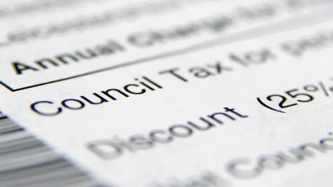 A close-up of a council tax statement on a table with most words blurred but "Council Tax" visible.