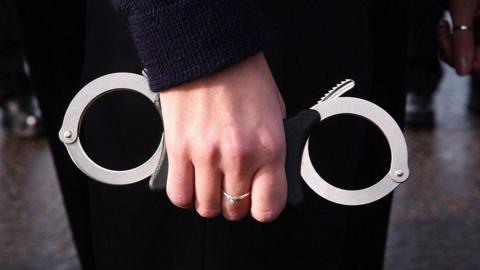 A police officer's hand holding handcuffs