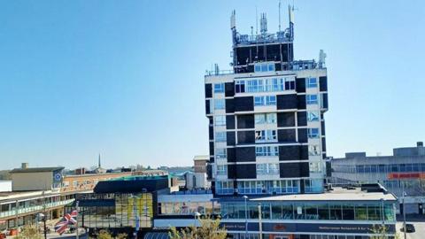 The outside of a building in Corby, with several stories tall made from glass and brick.