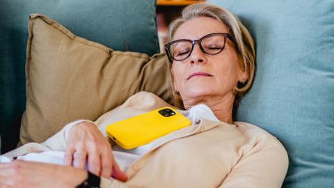 A woman napping on the sofa with a mobile phone