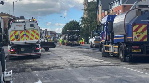 Oxford Road in Reading with several highway workers and trucks doing resurfacing work.