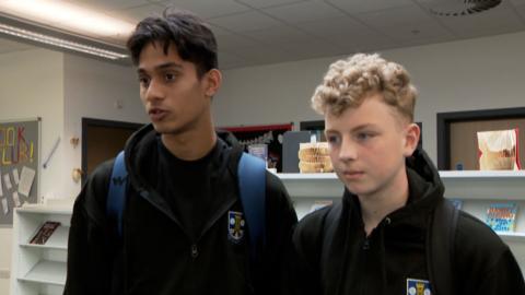 Two school children standing in a library
