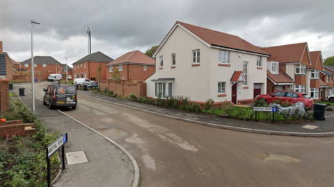 A junction at the end of a residential street. There are road signs that read "Martial Road" on either side of the junction, as well as houses on both sides too.