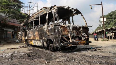 The wreckage of a burnt bus is pictured along a street after recent violence in Imphal in the Indian state of Manipur on June 8, 2025