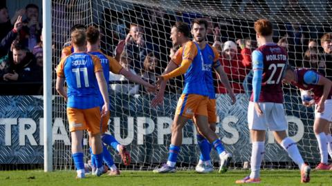 Shrewsbury players, including Anthony Scully (wearing no.11) congratulate Tom Sang for scoring as South Shields player Luke Woolston (no.27) looks on