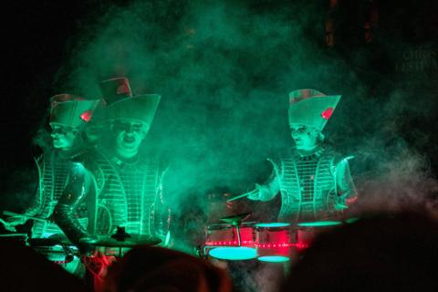 Threee illuminated drummers playing during a halloween festival