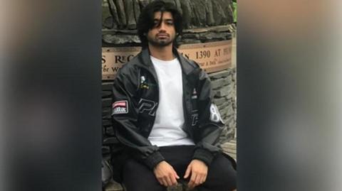 Aryan Sharma wearing a black jacket with a blurred background