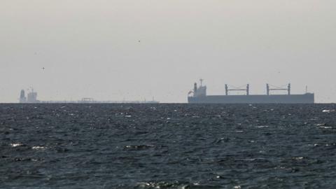 A cargo ship is seen on the horizon in the Gulf, near the Strait of Hormuz