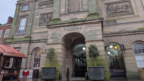 The stone entrance to the Guildhall Theatre in Derby, with black and gold gates signalling its long-term closure.