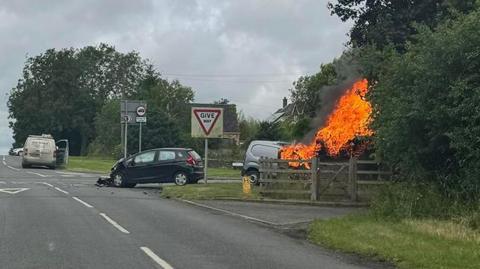 Scene of crash with one of the two vehicles on fire