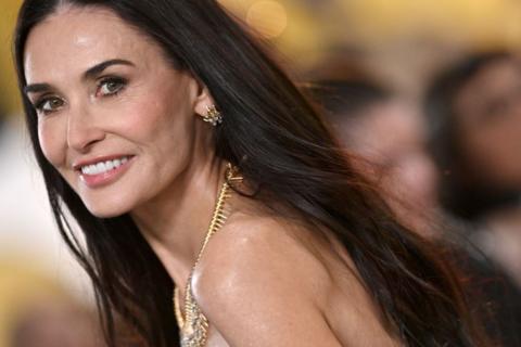 Demi Moore smiles - she has long dark hair and wears a gold necklace 