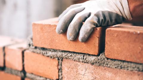 Close up of industrial bricklayer installing bricks on construction site.