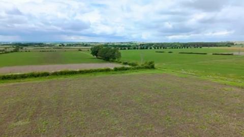 A landscape view of the Viking Way trail shows a cloudy sky, grassy land and vegetation with a walking path in the centre.