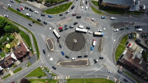 Aerial view of roundabout, with cars going around it.