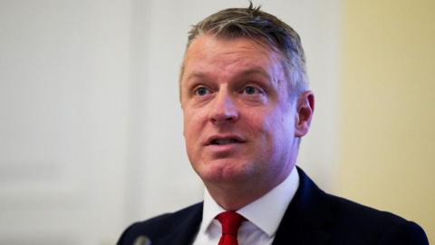Defence Minister Luke Pollard, with short grey hair, wearing a white shirt, red tie and black suit. 