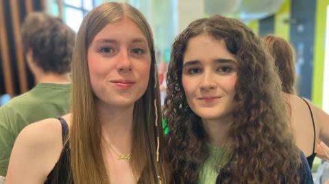 Two non-identical twins smile side by side on A-level results day.