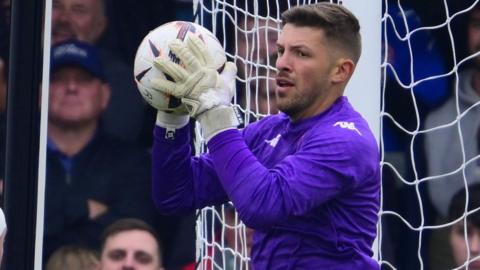 Dan Lavercombe grasping a football with both hands