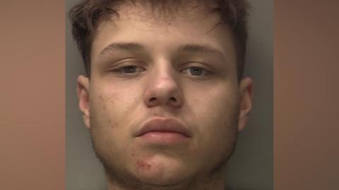 A police mug-shot of Corey Brown who has dark hair and is looking straight ahead.